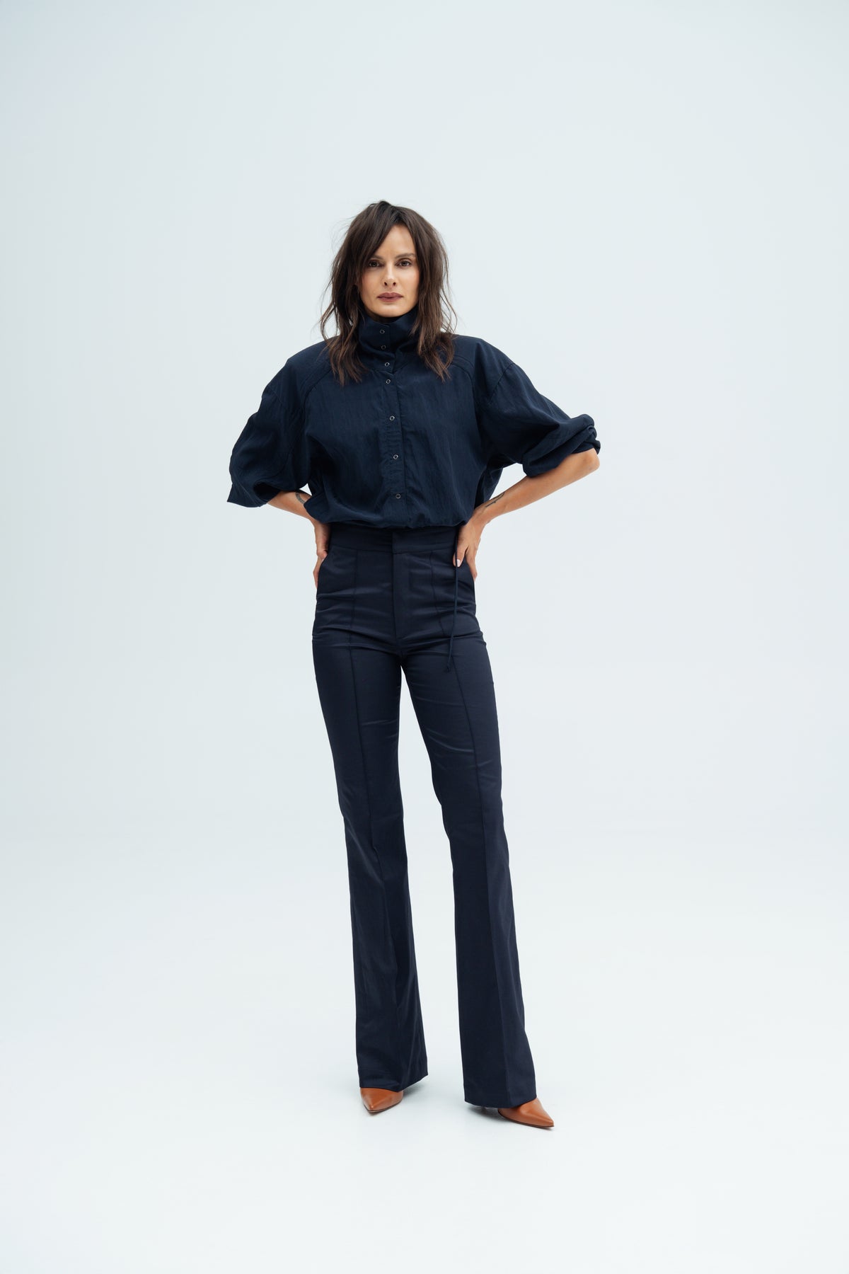 Model stands and  wears navy Enzy Pants and Nume shirt  by Resident Stranger.