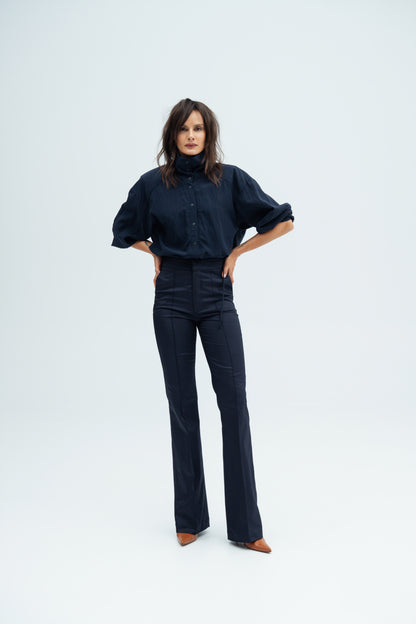 Model stands and  wears navy Enzy Pants and Nume shirt  by Resident Stranger.